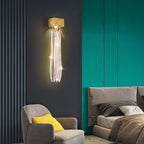 Slade branch crystal wall sconce - glass strand version lit above a grey armchair